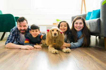 Cheerful family with young kids smiling relaxing in the living room with their beautiful cocker spaniel dogの写真素材