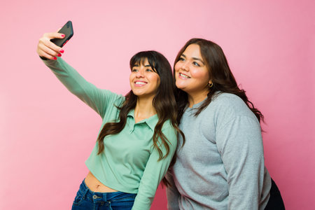 Attractive hispanic women friends smiling taking a selfie for social media with a smartphone o a...