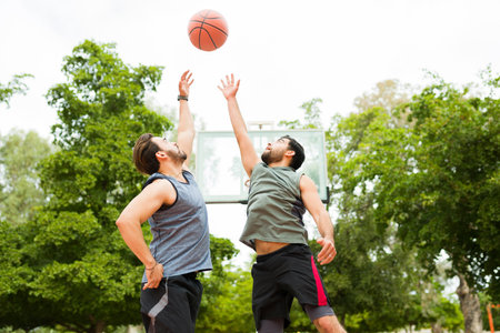 Fitness young men jumping to catch the ball while playing a one on one basketball game