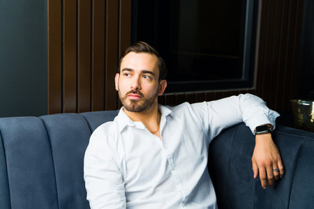 Attractive caucasian man sitting in an elegant classy place wearing formal clothes and looking sharpの写真素材