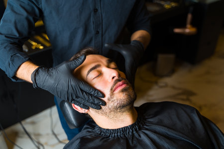 Relaxed handsome man getting a facial massage at the salon or barber shop before getting a haircut or shave his beardの写真素材