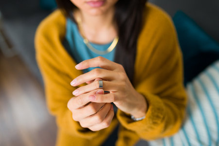 Close up of an hispanic woman looking sad and depressed taking off her wedding ring because of...