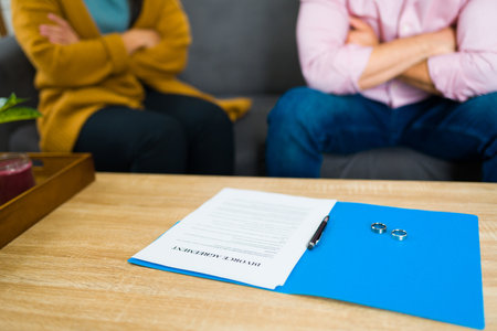 Close up of the divorce papers on the table while angry couple signing the legal papers after splitting up their marriageの写真素材