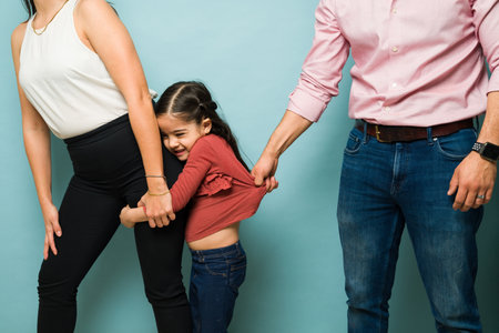 Angry young man trying to take away from her mother his scared sad kid holding hands with the mom because of domestic violenceの写真素材
