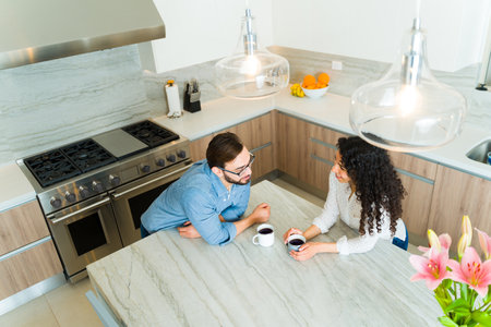 Top view of a happy couple drinking coffee on the granite kitchen island in the morning while looking in loveの写真素材