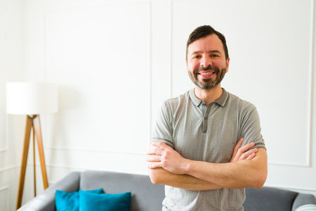 Attractive caucasian man in his 30s smiling looking happy and relaxing at his new home while making eye contactの写真素材