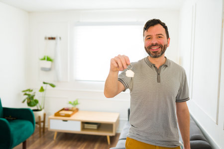 Caucasian attractive man looking excited after receiving the keys to his new home after movingの写真素材