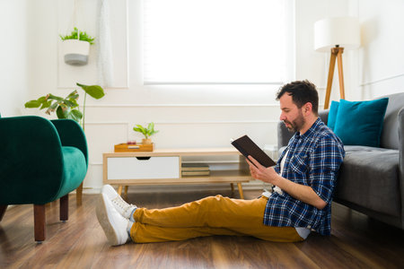 Side view of a relaxed caucasian man relaxing at home while enjoying reading a good book in the living roomの写真素材