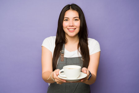 Attractive happy woman smiling making eye contact working as a barista at the coffee shopの写真素材