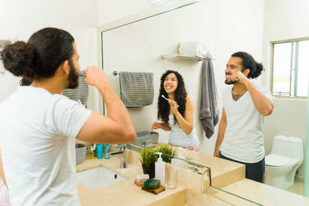 Cheerful couple laughing and having fun in the bathroom while brushing their clean teethの写真素材