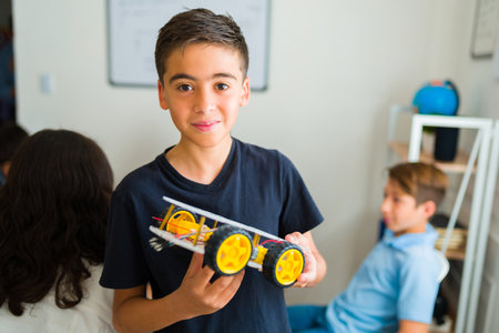 Portrait of a latin young teen boy smiling making eye contact building a robot in his electronics...