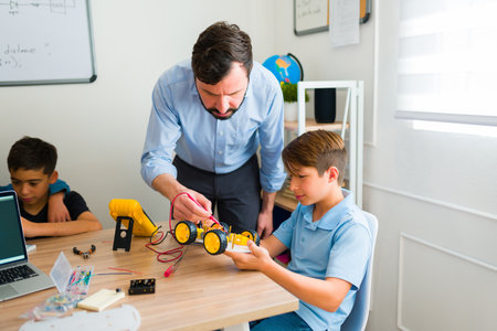 Hispanic teacher talking with a teen student about a robot prototype while teaching and learning during a robotics courseの写真素材