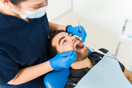 High angle of an hispanic man and patient coming to the dentist for a dental examination checking for cavitiesの写真素材