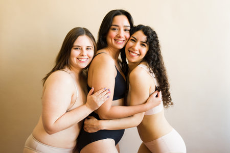 Cheerful attractive women in underwear hugging with a message of self-love and body diversity acceptanceの写真素材