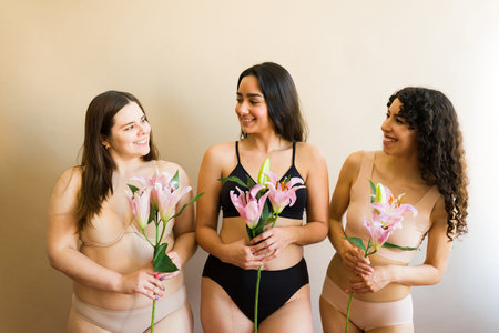 Happy diverse three women holding flowers feeling femenine and happy about body diversity and self loveの写真素材