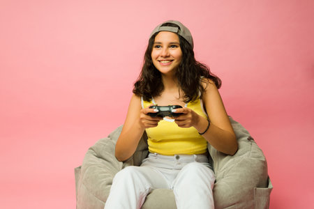 Excited teen girl and gamer relaxing on a bean bag and playing video games and having fun laughingの写真素材
