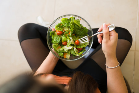 Top view of a fit woman with a healthy vegetarian lifestyle eating a green organic salad after exerciseの写真素材