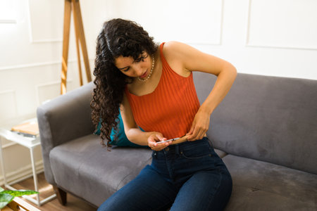Ill sick young woman with diabetes putting an insulin injection shot in her abdomen to maintain her blood glucose sugar levelsの写真素材