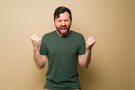 Smiling mid adult man screaming with happiness and feeling excited after receiving good news and celebratingの写真素材