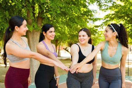 Beautiful diverse women happy about body positivity putting their hands together and celebrating with a high five exercising or running outdoorsの写真素材