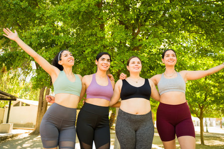 Beautiful happy group of diverse women with different bodies celebrating looking cheerful after running or exercising in the parkの写真素材