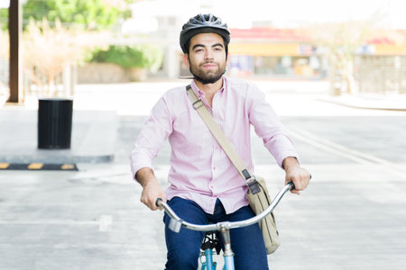 Casual business man smiling wearing a helmet while riding his bicycle commuting to work looking happyの写真素材