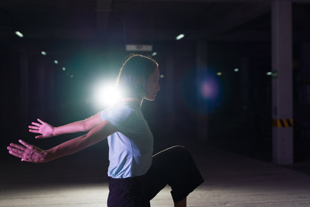 Profile of an artistic urban performer in action dancing at night while doing a cool modern dance on stageの写真素材