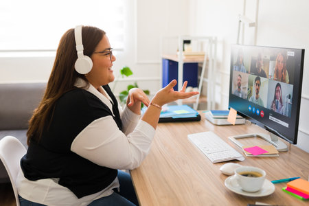 Professional big woman with headphones talking about her business and work during an online video...