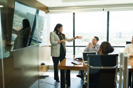 Asian female business professional giving a presentation to coworkers in boardroom at office
