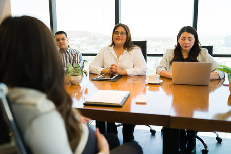 Human Resources representatives listening to pregnant female candidate during job interview at officeの写真素材