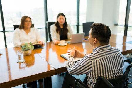 Disabled person in wheelchair answering questions to the team of recruiters at office during a...