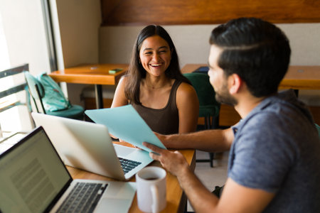 Happy couple laughing having fun while using the wifi zone and doing remote work together at the...