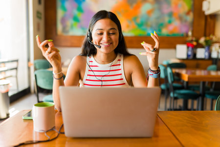 Cheerful woman working as a customer service agent doing remote work and talking wearing a headset and while smilingの写真素材
