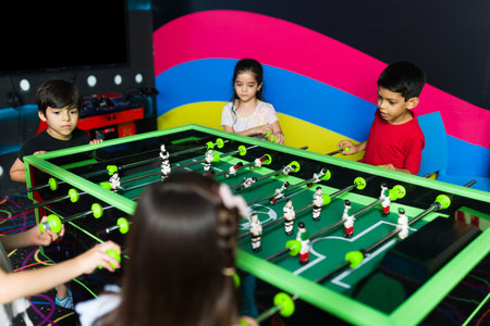 Group of kids playing foosball together and having fun during a competition game in the arcadeの写真素材