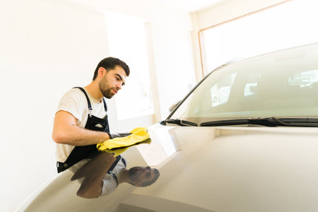 Professional male worker drying the water of a vehicle after cleaning it at the car wash at the auto detail serviceの写真素材