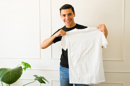 Happy caucasian man showing a white mockup t-shirt with copy space for a designの写真素材