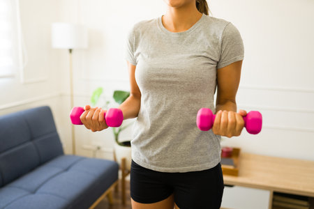 Young hispanic woman wearing a gray mock-up t-shirt for a design copy space exercising lifting dumbbells weightsの写真素材