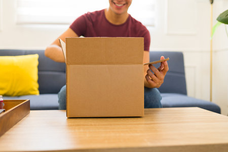 Close up of a young man at home opening a mockup box package ready for a copy space designの写真素材
