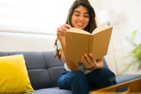 Beautiful happy woman reading a book showing the mock-up blank cover with copy spaceの写真素材