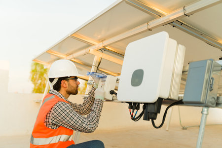 Professional engineer and solar panel installer working on the electrical connection of the...