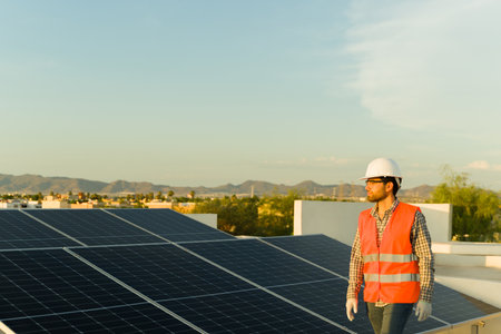 Handsome young man working as an engineer working at a residential home installing solar panels and photovoltaic cellsの写真素材