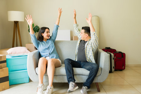 Beautiful wife and husband celebrating buying furniture while moving boxes to their new house after getting a mortgage creditの写真素材