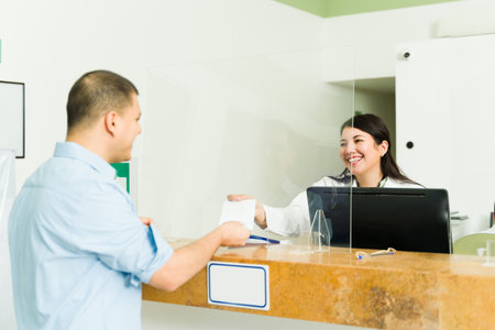 Smiling young woman with a white coat giving his test results to a male patient at the reception desk of the medical labの写真素材