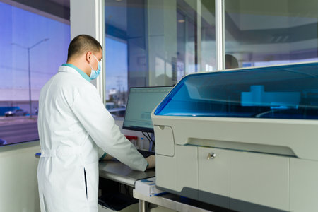 Lab technicianor chemist seen from behind working with equipment in the medical laboratory while...