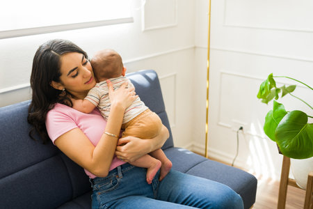 Beautiful caucasian mother trying to put to sleep her tired adorable baby and singing a lullaby...
