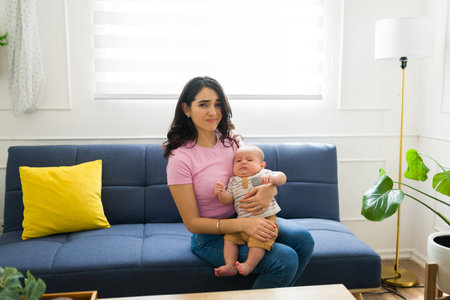 Tired young mother feeling overwhelmed and exhausted because of taking care of children and...