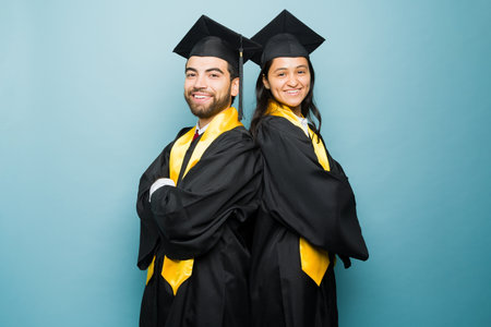 Smart hispanic couple feeling proud after finishing college together wearing black graduation gown...