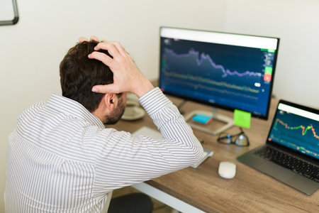 Stressed caucasian man screaming and worrying about investing while checking the stock market in the...