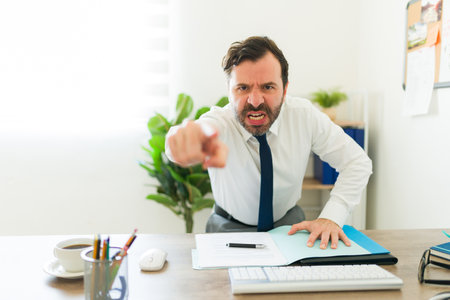 Angry boss or business supervisor pointing and firing people looking upset after having work problemsの写真素材