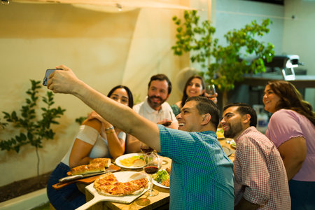 Dinner host taking a selfie with his group of friends coming to eat and drink alcohol at his home...